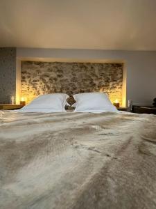 a large bed with two pillows and a stone wall at Superbe appartement avec spa privatif in Vincelles