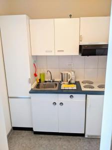 eine Küche mit weißen Schränken und einem Waschbecken in der Unterkunft Seehütte Ferienwohnung 507 in Cuxhaven