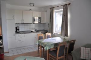 eine Küche mit einem Tisch und Stühlen sowie eine Küche mit weißen Schränken in der Unterkunft Nordseedüne, Ferienwohnung 3 in Cuxhaven