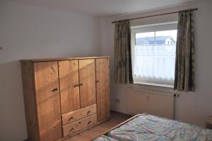 ein Schlafzimmer mit einem Holzschrank und einem Fenster in der Unterkunft Nordseedüne, Ferienwohnung 3 in Cuxhaven