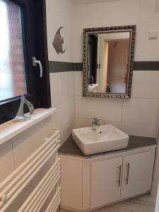 uma casa de banho com um lavatório e um espelho em Kampweg 4 em Cuxhaven