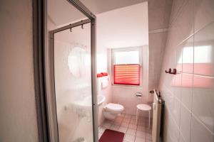 La salle de bains est pourvue de toilettes et d'une porte de douche en verre. dans l'établissement Dünenglück, Ferienwohnung 33, à Cuxhaven