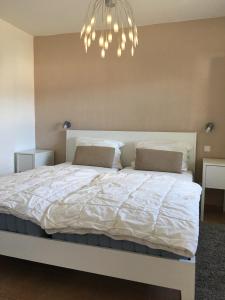 sypialnia z białym łóżkiem i żyrandolem w obiekcie Satelsrönne 8 w mieście Cuxhaven