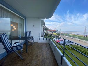 balcón con mesa y sillas y vistas a la playa en Nautilus, Ferienwohnung 12 inkl Strandkorb, en Cuxhaven