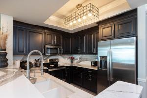 a kitchen with black cabinets and a stainless steel refrigerator at Phoenix Gulf Towers 2502 condo in Gulf Shores