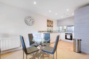 een keuken en eetkamer met een glazen tafel en stoelen bij Alder House Serviced Apartment Maidenhead by 360stays in Maidenhead