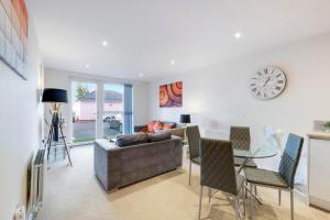 een woonkamer met een bank en een klok aan de muur bij Alder House Serviced Apartment Maidenhead by 360stays in Maidenhead