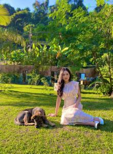 a woman sitting on the grass next to a dog at Eco Rose Homestay in Diện Biên Phủ