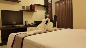 Cette chambre d'hôtel comprend un lit avec des cygnes fabriqué à partir de serviettes. dans l'établissement Leelawadee Modern Resort Huaykwang, à Bangkok
