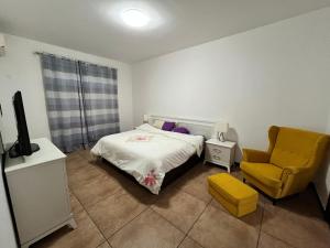 a bedroom with a bed and a yellow chair at APARTMENTO LUMINOSO in Ciudad de Malabo