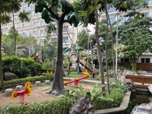 un parque con juegos infantiles y un árbol en Cool 1BR Acqua Livingstone w/ Netflix, Pool & Gym, en Manila