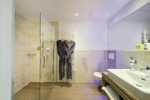 un bagno con doccia in vetro e lavandino di Active Nature Resort DAS SeeMOUNT a See