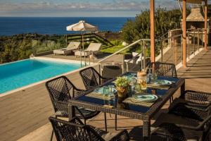 a table and chairs on a deck next to a pool at Entheos Private Villa Fiskardo Kefalonia Greece in Fiskardho