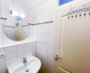 Un baño blanco con lavabo y espejo. en hochwertig ausgest. App. mit WLAN und kostenl. Stellplatz, en Heringsdorf 5 fotos más
