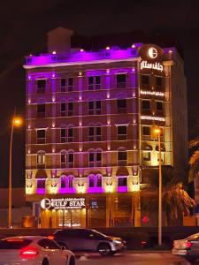 جلف ستار للشقق المخدومة GULF STAR APARTMENTs في الرياض: مبنى أرجواني مضاء عليه علامة نجمة داكنة