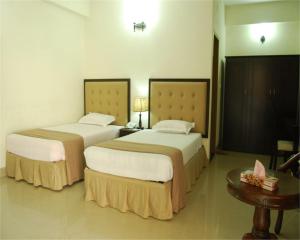 Habitación de hotel con 2 camas y mesa en Ambassador en Chittagong