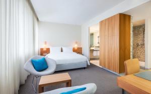 een hotelkamer met een bed en een stoel bij Lindner Hotel Berlin Ku'damm, part of JdV by Hyatt in Berlijn