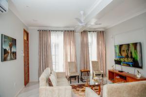 ein Wohnzimmer mit weißen Möbeln und einem Deckenventilator in der Unterkunft Mahogany Mine Apartments-3 in Daressalam