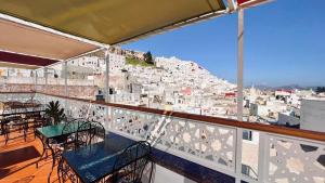 a balcony with tables and chairs and a view of a city at Riad Amelia - Lalla Amelia Room in Tetouan