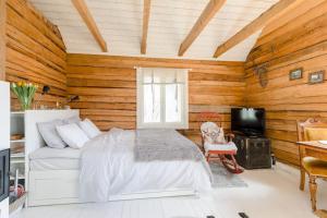 a bedroom with wooden walls and a bed and a television at Romantic cottage with sauna in Porvoo