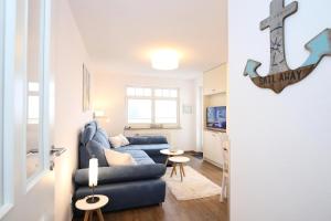 Villa Hanse Wohnung 313 في كولونغسبورن: غرفة معيشة مع أريكة زرقاء وعبارة على الحائط