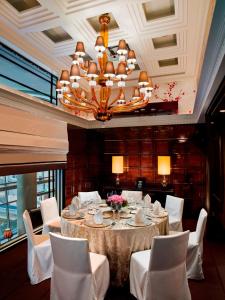 a dining room with a table with white chairs and a chandelier at The Fullerton Bay Hotel Singapore in Singapore