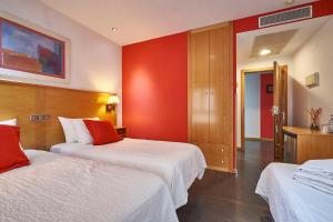 Habitación de hotel con 2 camas y pared roja en Hotel Real de Illescas, en Illescas