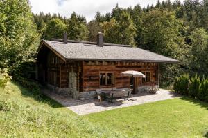 Cabaña de madera con mesa de picnic y sombrilla en Wochenbrunner Chalets en Ellmau