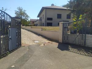 a gate in a driveway with a house in the background at Suite Mansardée indépendante, 25min Lyon-Villefranche in Chazay-dʼAzergues