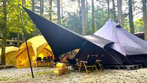 a group of tents and chairs in a forest at Work Shop Camp Resort Forest and Lake Paradise - Vacation STAY 85274v in Fujikawaguchiko