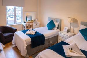 a bedroom with two beds and a chair and a window at OYO Lonsdale Guest House in Oxford