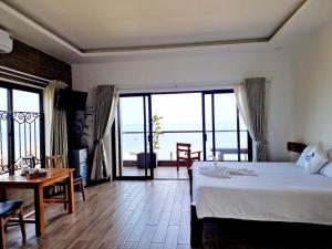 a bedroom with a bed and a table and a balcony at Butterfly Rose Beach Resort Phú Quốc Francophone in Phu Quoc