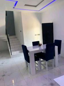 una mesa blanca con sillas azules en una habitación en Belle villa neuve meublée à Baguida en Baguida