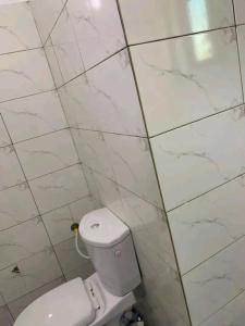 baño con aseo en una pared de azulejos blancos en Belle villa neuve meublée à Baguida en Baguida