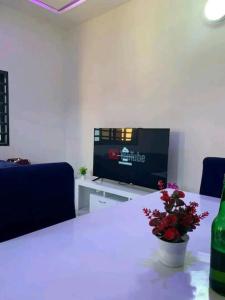 Habitación con mesa, TV y mesa con flores. en Belle villa neuve meublée à Baguida en Baguida