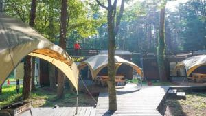 Work Shop Camp Resort Forest and Lake Paradise - Vacation STAY 85273v في فوجيكاواجوتشيكو: مجموعة من الخيام في حديقة مع شرفة خشبية