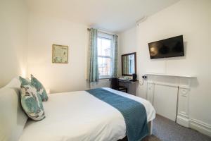 a bedroom with a bed and a tv on the wall at OYO Lonsdale Guest House in Oxford