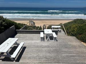 a group of picnic tables and benches on the beach at The Dunes Resort - Forest View in Plettenberg Bay