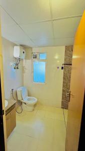 a bathroom with a toilet and a window at THE HONEY HOMES in Noida