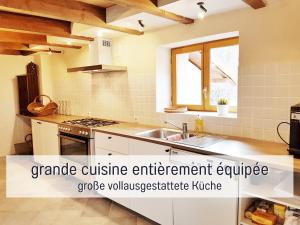 een keuken met witte kasten, een wastafel en een raam bij Chez Louna - Grand Gîte in Aumontzey
