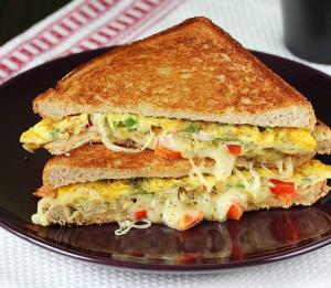 a sandwich cut in half on a black plate at Rashiva Resort in Arambol