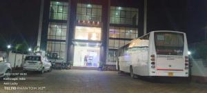 a white bus parked in front of a building at night at J P PALACE in Kushinagar