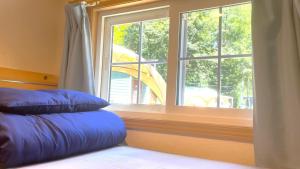 łóżko z niebieskimi poduszkami przed oknem w obiekcie Work Shop Camp Resort Forest and Lake Paradise - Vacation STAY 85272v w mieście Fujikawaguchiko