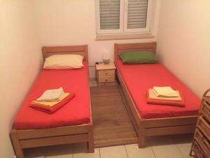 twee bedden in een kleine kamer met rode lakens bij Matea in Novalja