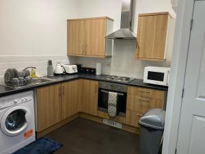 a kitchen with wooden cabinets and a washer and dryer at Branxiar Suite - 1bedroom Executive Suite & Apartment in Wallsend in Old Walker