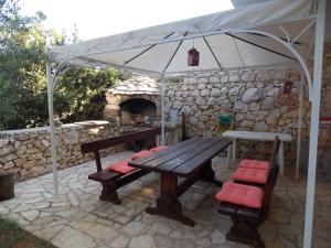 een picknicktafel met parasol en een stenen open haard bij Matea in Novalja