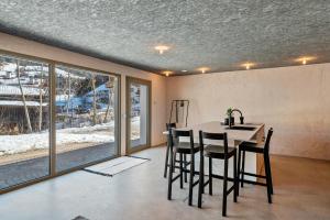 a dining room with a table and chairs and windows at Lena Dolomites Gartensuite in Villnoss