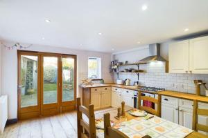 a kitchen with white cabinets and a table in it at Melody Rowe One Bed Free Wi-Fi Garden Fireplace 