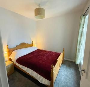 um quarto com uma cama com um cobertor vermelho em House in Ebbw Vale em Ebbw Vale
