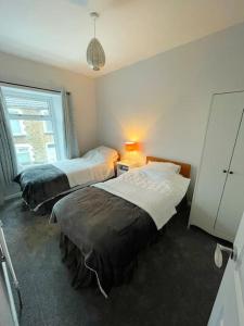 a bedroom with two beds and a lamp and a window at House in Ebbw Vale in Ebbw Vale